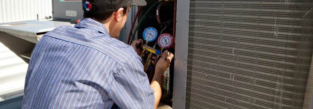 HVAC technician servicing a condenser unit in Salamanca