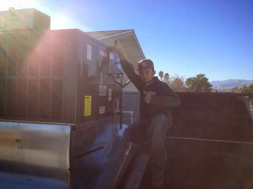 HVAC technician performing Air Duct Repair on a rooftop unit in Salamanca